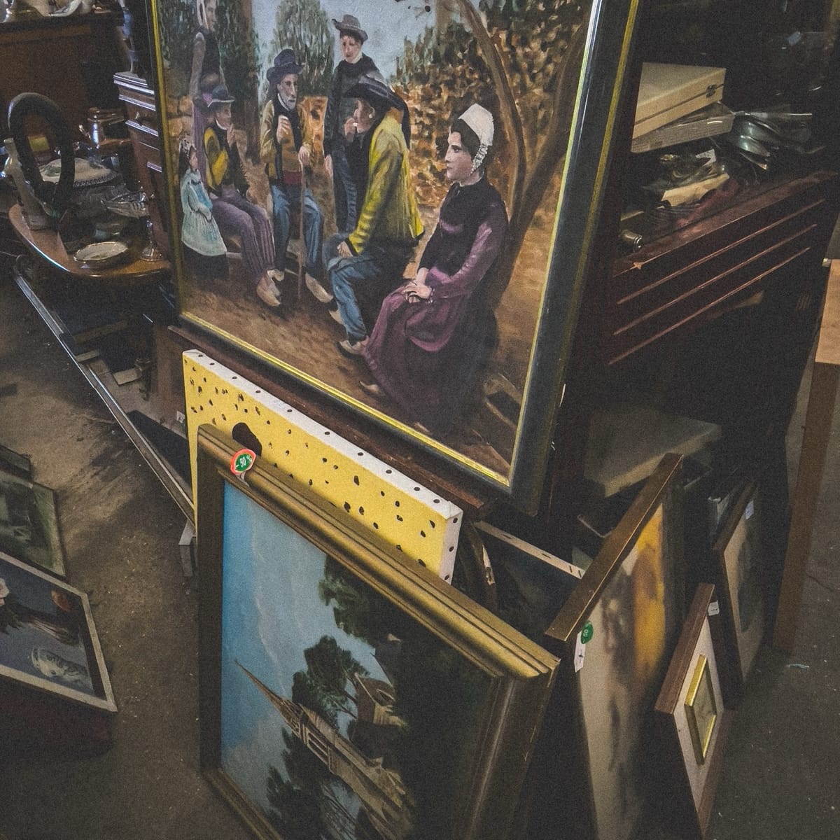 Tableaux bretons anciens posés sur un meuble de débarras dans une brocante à Douarnenez