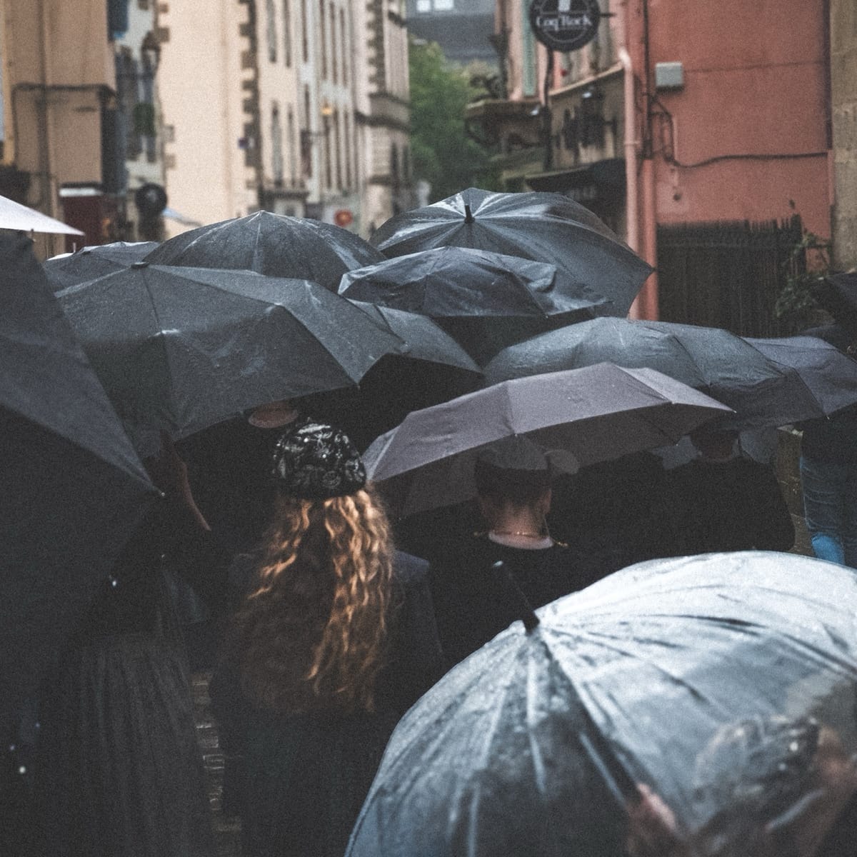 Parapluies noirs sous la pluie à Quimper, foule ralentie dans le centre-ville