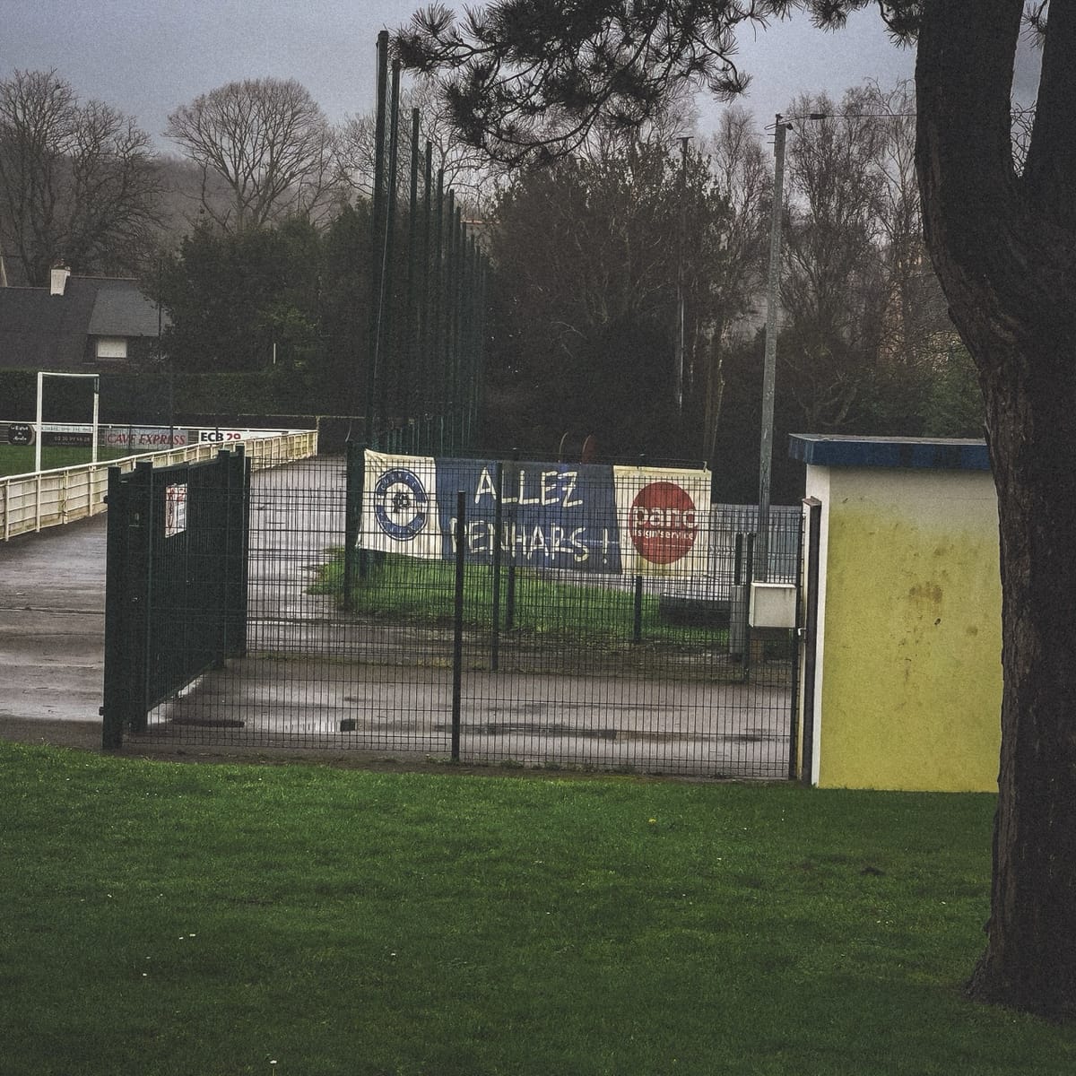 Stade de Penhars fermé sous la pluie à Quimper, banderole "Allez Penhars" accrochée au grillage